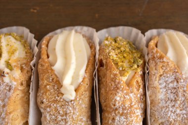 Dört Cannoli 'yi kapayın. Ahşap bir arka planda, güzel bir kağıda yeni sergilenmiş.