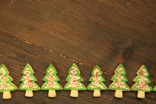 Reihe Von Weihnachtsbaumplätzchen Mit Zuckerguss Auf Einem Hölzernen Tischhintergrund — Stockfoto