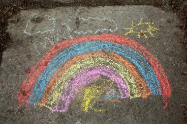 Çocuk tarafından renkli tebeşirlerle yapılmış bir kaldırımda gökkuşağı