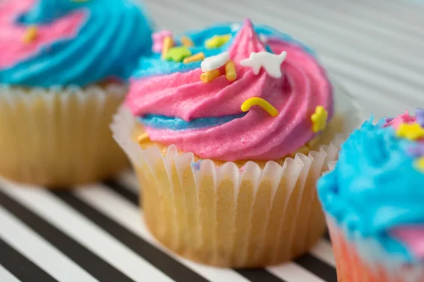 黒と白の裏地にブルーとピンクのアイシングのカップケーキ — ストック写真