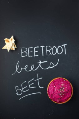 Siyah zemin üzerinde pita olan pancar kökü humusunun en üst görüntüsü. Tebeşirle daha iyi ayak, pancar ve pancar yazılıyor.