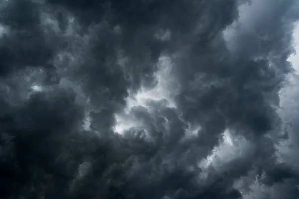 Wolken mit Hintergrund, Sonnenlicht durch sehr dunkle Wolken Hintergrund durch dunkle Gewitterwolken, schwarzer Himmel Hintergrund durch dunkle Wolken vor einem Donner. — Stockfoto