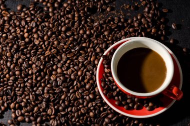 Sıcak kahve kırmızı Kupası ve kahve çekirdekleri arka plan vardır.