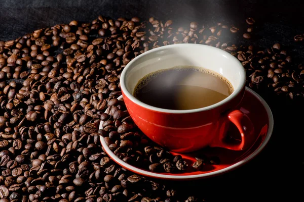Forró kávé szemes kávé és piros pohár vagy a háttér. — Stock Fotó