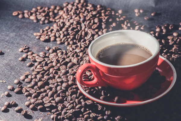 Hot coffee in red cup and coffee beans are the background. — Stock Photo, Image