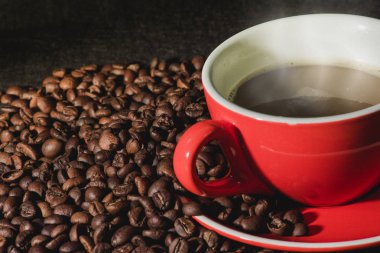 Sıcak kahve kırmızı Kupası ve kahve çekirdekleri arka plan vardır.