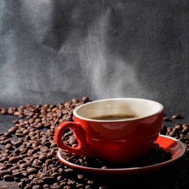 Sıcak kahve kırmızı Kupası ve kahve çekirdekleri arka plan vardır.