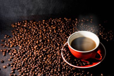 Sıcak kahve kırmızı Kupası ve kahve çekirdekleri arka plan vardır.