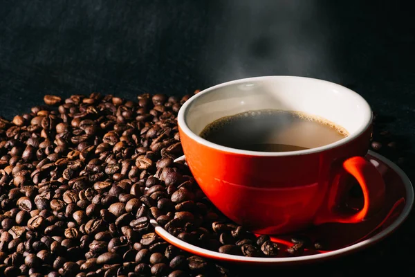 Sıcak kahve kırmızı Kupası ve kahve çekirdekleri arka plan vardır.