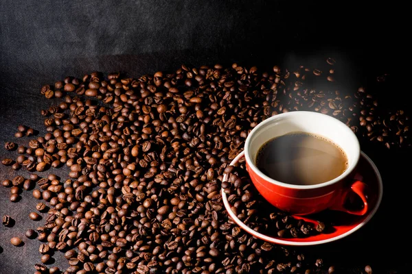 Sıcak kahve kırmızı Kupası ve kahve çekirdekleri arka plan vardır.