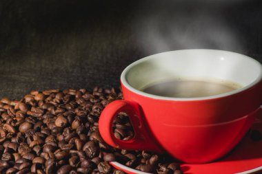 Sıcak kahve kırmızı Kupası ve kahve çekirdekleri arka plan vardır.