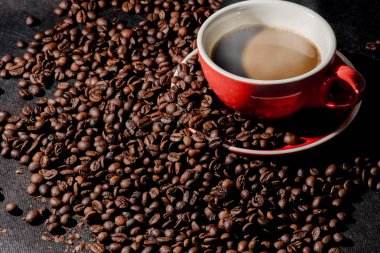 Sıcak kahve kırmızı Kupası ve kahve çekirdekleri arka plan vardır.