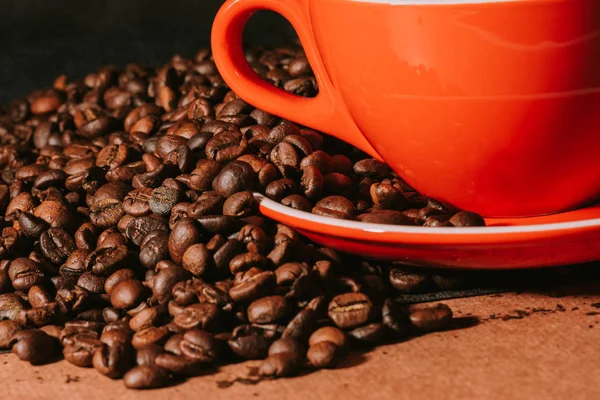 Caffè caldo in tazza rossa e chicchi di caffè sono lo sfondo . — Foto Stock