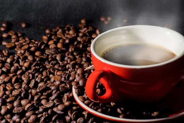 Forró kávé szemes kávé és piros pohár vagy a háttér. — Stock Fotó