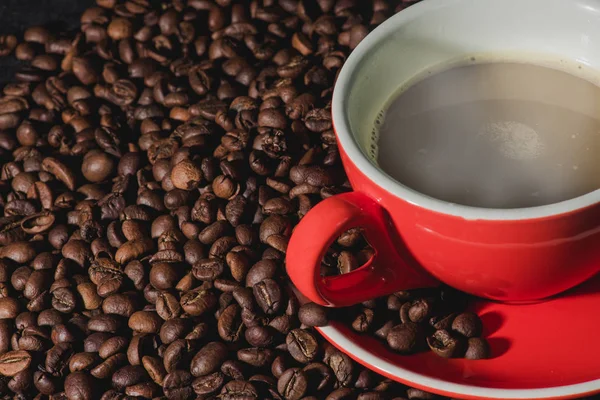 Sıcak kahve kırmızı Kupası ve kahve çekirdekleri arka plan vardır.