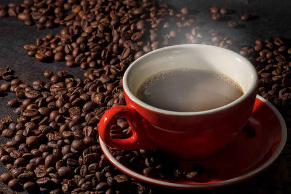 Gorąca kawa w czerwony kubek i ziarna kawy są tłem. — Zdjęcie stockowe