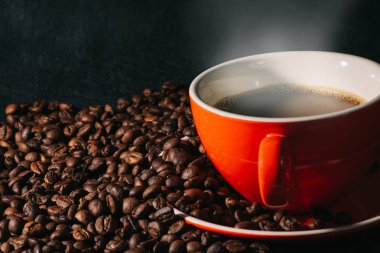 Sıcak kahve kırmızı Kupası ve kahve çekirdekleri arka plan vardır.