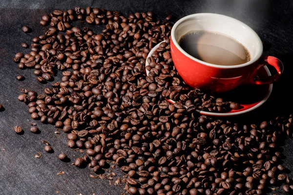 Sıcak kahve kırmızı Kupası ve kahve çekirdekleri arka plan vardır.