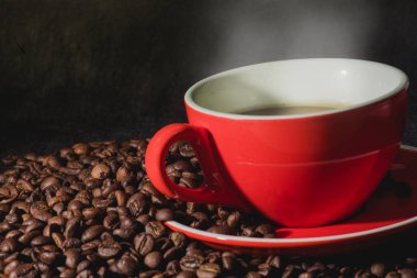 Sıcak kahve kırmızı Kupası ve kahve çekirdekleri arka plan vardır.