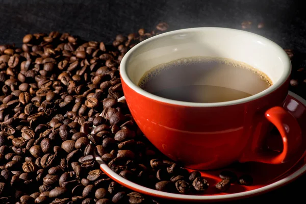 Gorąca kawa w czerwony kubek i ziarna kawy są tłem. — Zdjęcie stockowe