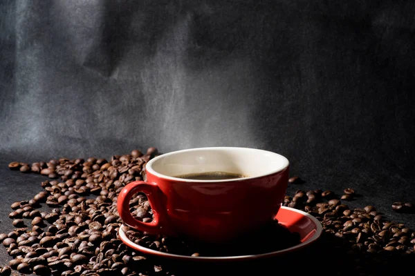 Sıcak kahve kırmızı Kupası ve kahve çekirdekleri arka plan vardır.