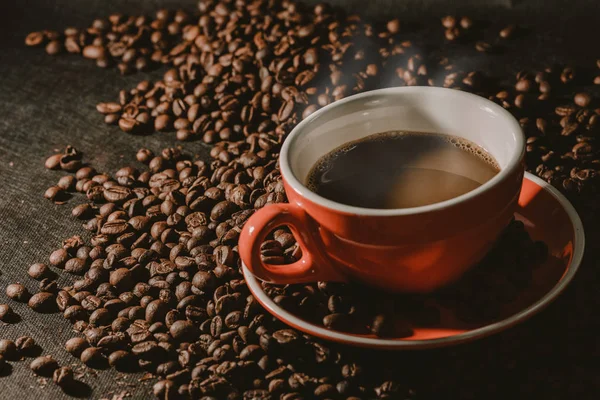 Sıcak kahve kırmızı Kupası ve kahve çekirdekleri arka plan vardır.