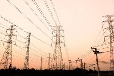 Gökyüzü günbatımı arka planında yüksek voltaj direği.