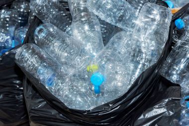 Siyah çöp torbalarındaki plastik şişeler geri dönüşüm için alınmayı bekliyor..
