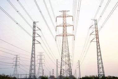 Gökyüzü günbatımı arka planında yüksek voltaj direği.