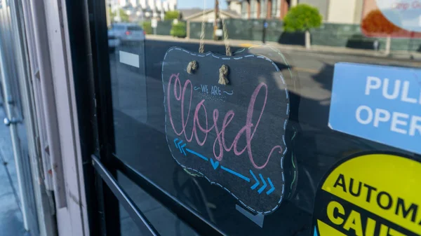 Bir mağazanın cam kapısında dekoratif ahşap kapalı tabela.