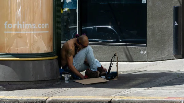 A homeless man with bandana sleeping on the street on a summer day — Stock Photo, Image