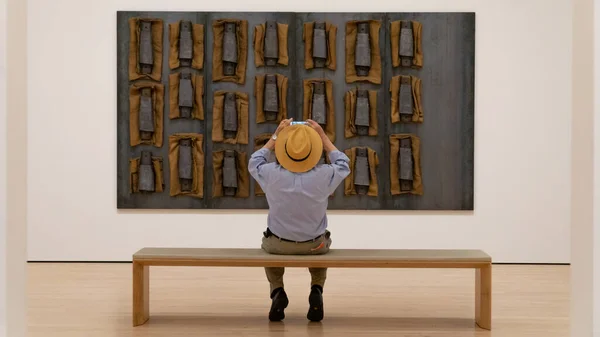 Hombre con sombrero tomando fotos de una obra de arte en el Museo de Artes Modernas de San Francisco Fotos de stock