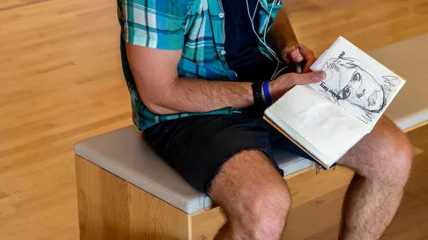 San Francisco Modern Sanatlar Müzesinde Debbie Harry 'nin çizimini yapan şortlu genç adam.