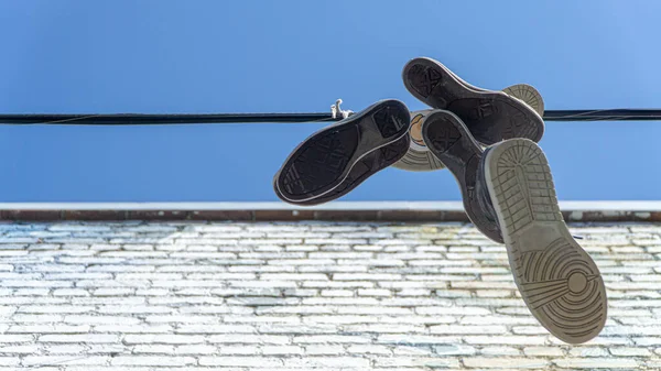 Zapatillas y zapatos viejos colgados de un alambre —  Fotos de Stock