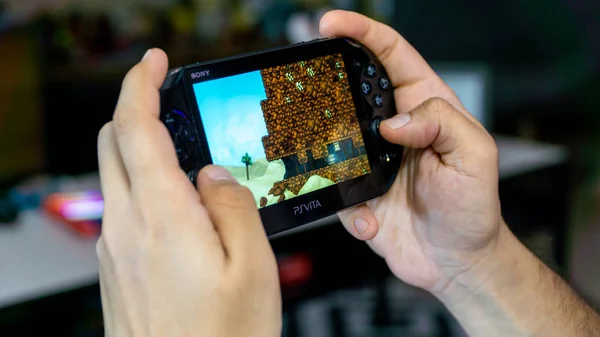 Guy playing Spelunky on Sony PS Vita - handheld playstation gaming console — Stock Photo, Image