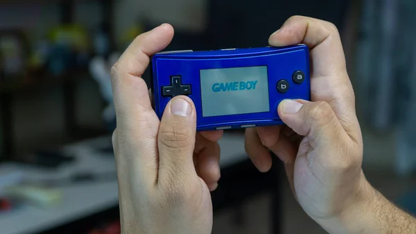 Hombre jugando con Nintendo Gameboy Micro - la consola de mano más pequeña Imagen de archivo