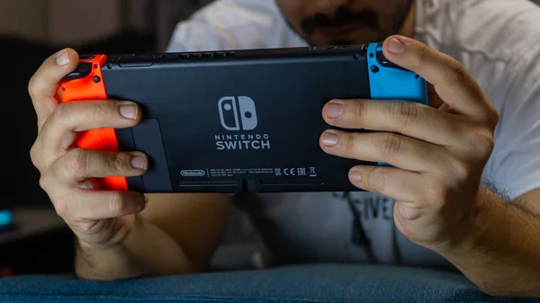 Cara jogando com Nintendo Switch - um console de jogos de mão — Fotografia de Stock
