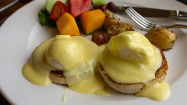 Yumurtalı Benedict 'i, iki yumurta ve pastırmalı kekin üstüne de hollandaise sosu ve ananas.