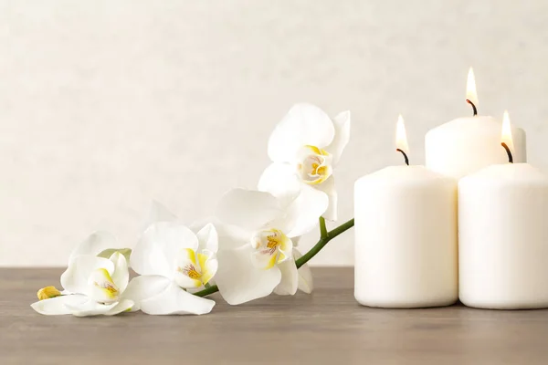 Çiçeklerle, orkidelerle ve yanan aromatik mumlarla dolu bir spa. Uzayı kopyala Orkidenin beyaz çiçekleri ve ahşap masa üzerinde mumlar.. 