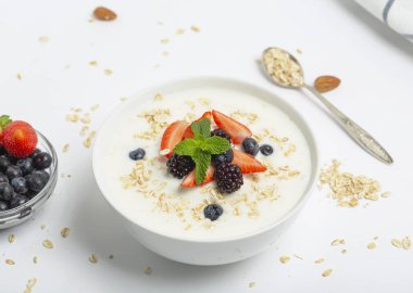 Mısır gevrekli yoğurt taze çilek, yabanmersini, böğürtlen ve beyaz masada badem. Sağlıklı atıştırmalıklar. Kahvaltı hazır.. 