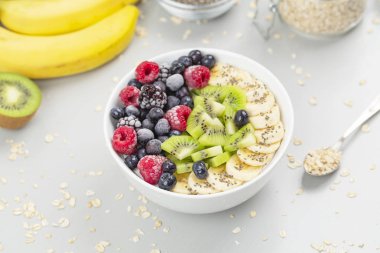 Ahududu, yabanmersini, kivi, muz, böğürtlen ve çekirdekli chia soslu sağlıklı kahvaltı smoothie kasesi. Vejetaryen yemeği. 