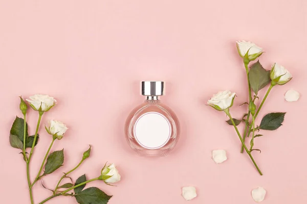 ピンクの背景に白いバラの香水のボトル フラットレイアウト トップビュー コピースペース ロイヤリティフリーのストック画像