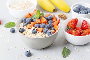 Sağlıklı meyve suyu kasesi granola, taze çilek, yabanmersini, muz, yoğurt ve nane. Sağlıklı yemek, atıştırmalık ya da kahvaltı. 