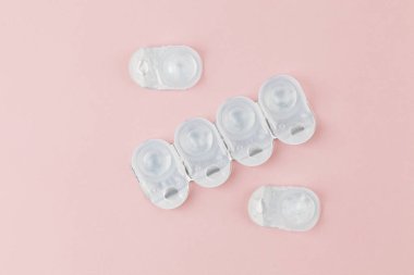 Kontakt lens paketleri pembe arkaplanlıdır. Bir yığın tek kullanımlık kontakt lens. Düz konum