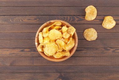 Ahşap arka planda çıtır patates cipsi. Tahta kasede patates cipsi, seçici bir odak noktası. Üst görünüm. 
