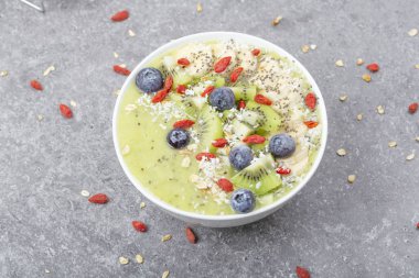 Kahvaltı kivili smoothie kasesi yulaf gevreği ve böğürtlenli. Muz, Goji üzümü, yabanmersini, Chia tohumu, hindistan cevizi ve müsli ile lezzetli kivili smoothie. Vejetaryen yemeği. 