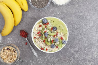 Kahvaltı kivili smoothie kasesi yulaf gevreği ve böğürtlenli. Muz, Goji üzümü, yabanmersini, Chia tohumu, hindistan cevizi ve müsli ile lezzetli kivili smoothie. Vejetaryen yemeği. 