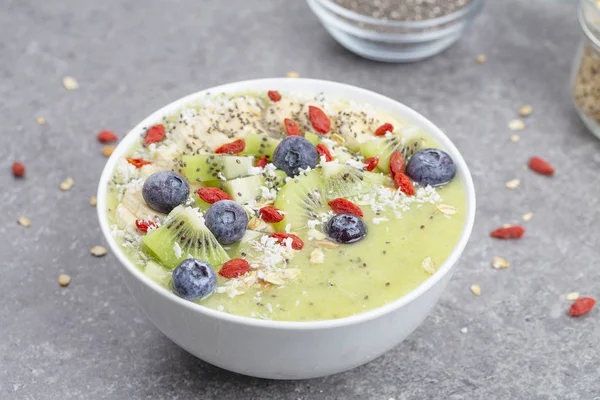 Kahvaltı kivili smoothie kasesi yulaf gevreği ve böğürtlenli. Muz, Goji üzümü, yabanmersini, Chia tohumu, hindistan cevizi ve müsli ile lezzetli kivili smoothie. Vejetaryen yemeği. 