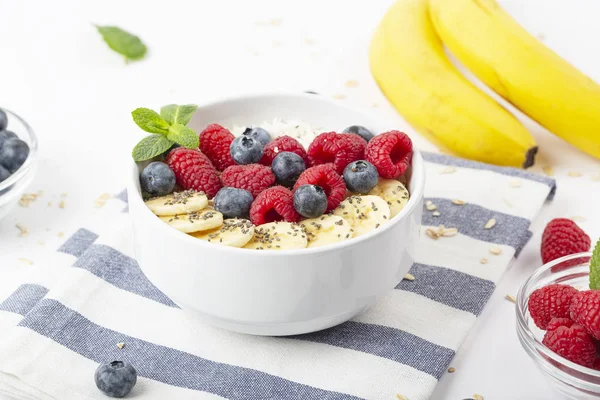 Breakfast smoothie with granola, yogurt, fresh raspberries, blueberries, bananas, coconut flakes, Chia seeds and mint. Healthy food. Breakfast food.