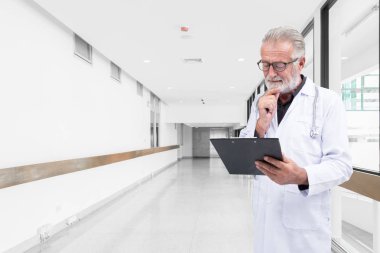 Kıdemli doktor hastane koridorunda bir tıbbi kayıt incelemek